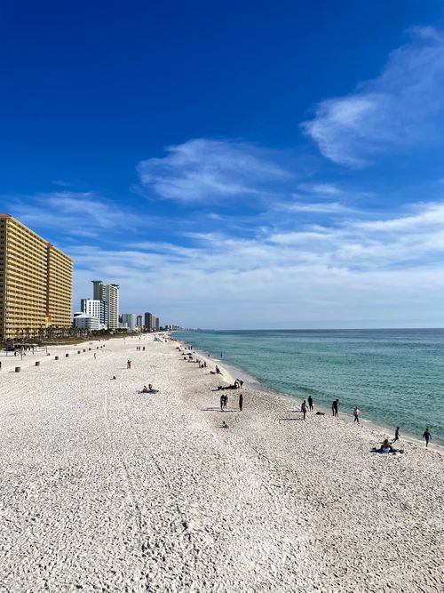 Free Beach scene with modern cityscape and blue skies, ideal for travel or urban lifestyle themes. Stock Photo