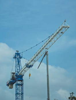 A blue tower crane standing tall against a clear blue sky, used in construction projects.