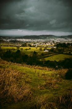在郁郁葱葱的绿色乡村上空，可以看到暴风雨的戏剧性场景和遥远的城镇景色