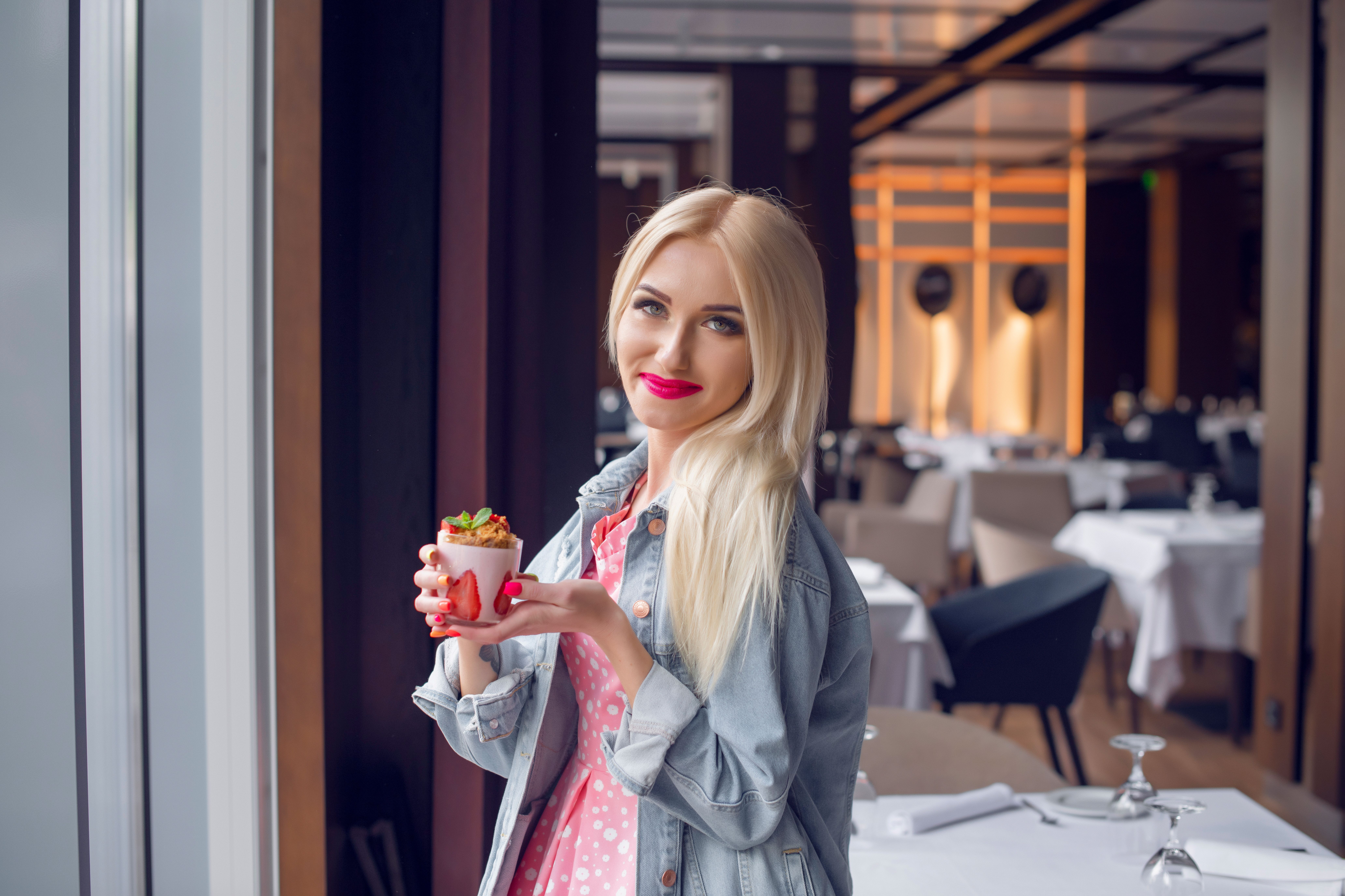 Blonde woman in a chic Parisian restaurant savoring a stylish dessert.