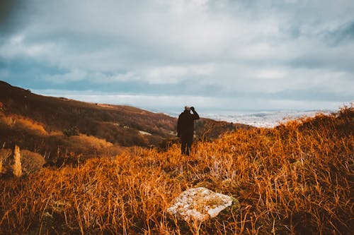 Man Standing on Brown Grass Field