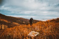 一位孤身的徒步旅行者站在秋叶中，俯瞰着广阔的风景