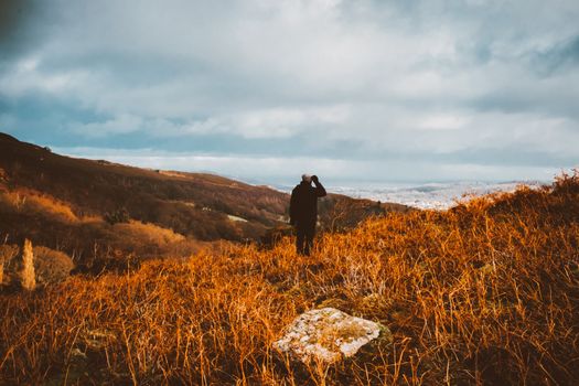 一位孤身的徒步旅行者站在秋叶中，俯瞰着广阔的风景