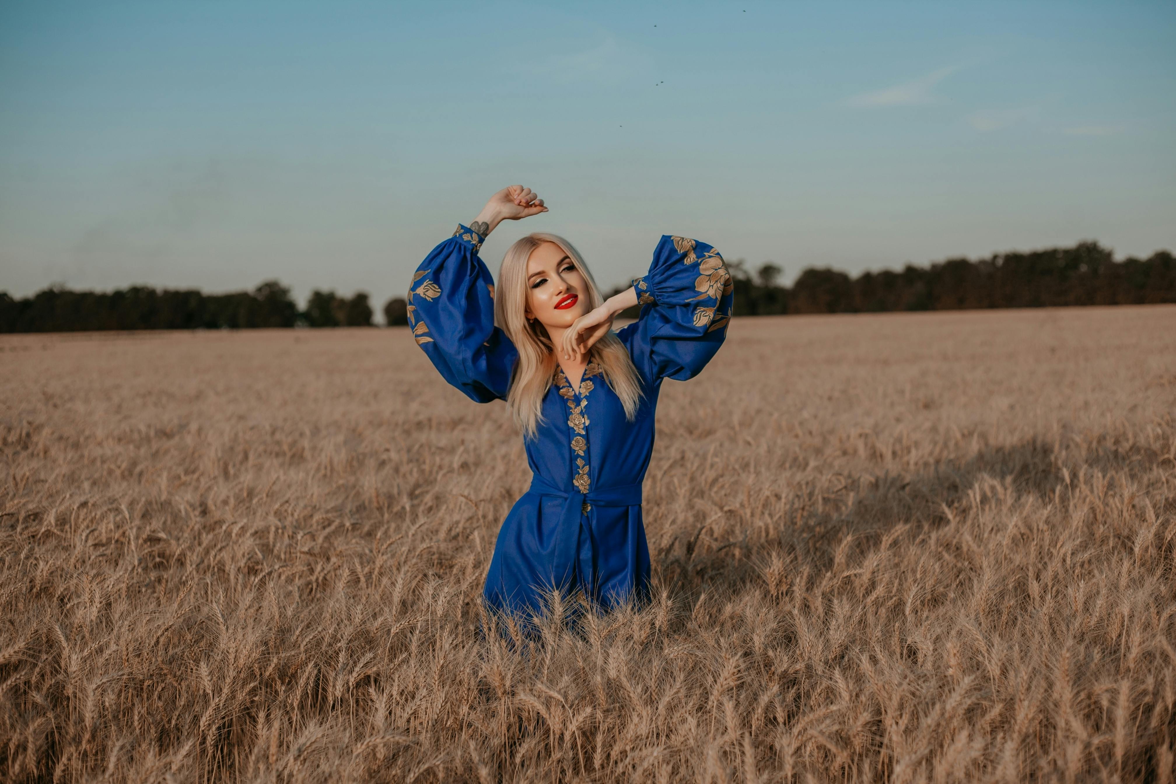 a woman in a blue dress is standing in a field