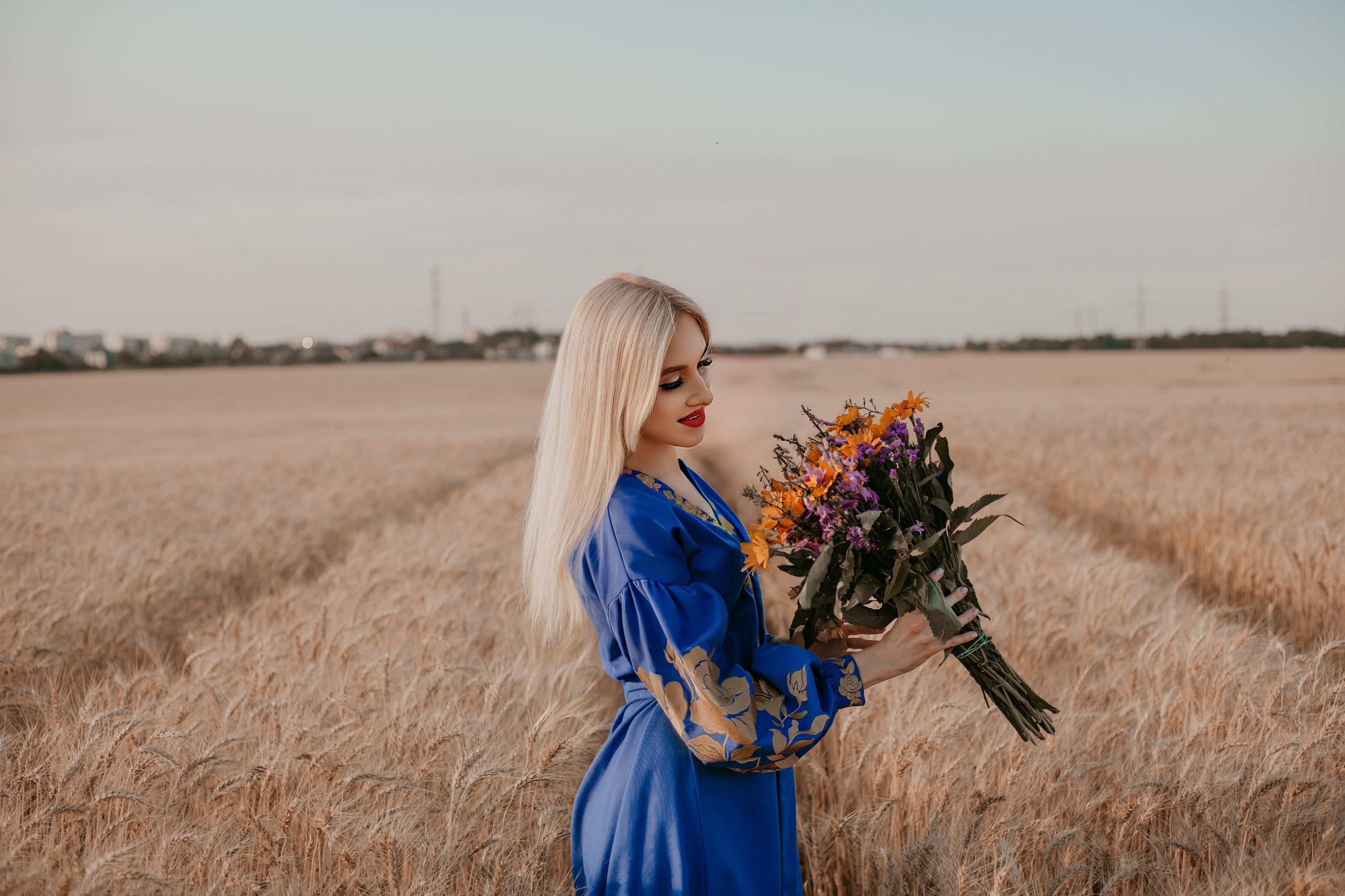 A blonde woman in a blue dress holding flowers in a field · Free Stock ...