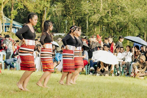 A Group of Dancers in Traditional Clothing Dancing on a Meadow 