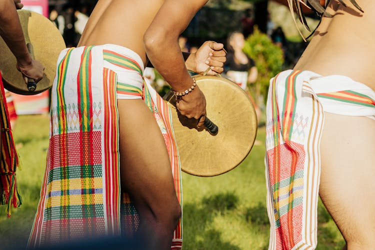 Close Up Of Man In Tribal Clothing Playing Drum