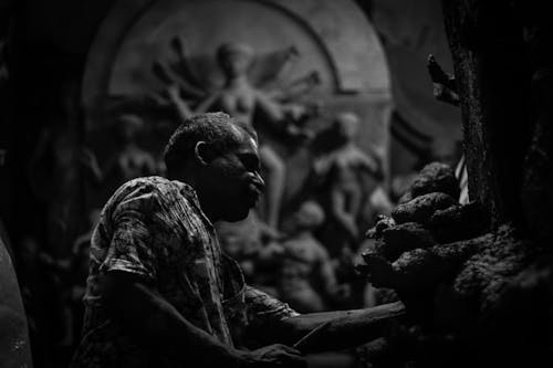 Black and White Photo of a Man and Sculptures