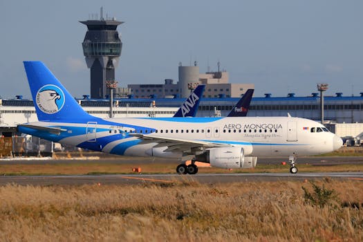 Aero Mongolia airplane on runway with airport terminal in background under clear sky.
