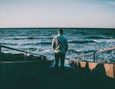 在宁静的日落中，一个人站在楼梯上凝视着大海