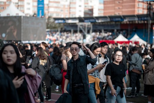 A lively crowd gathers in an urban stadium for an outdoor event, capturing the essence of city life.