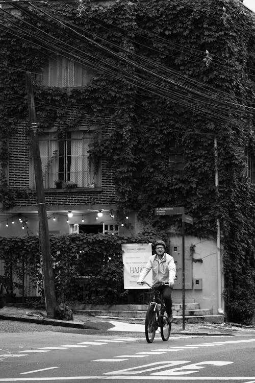 Man Cycling on Street in Town in Black and White