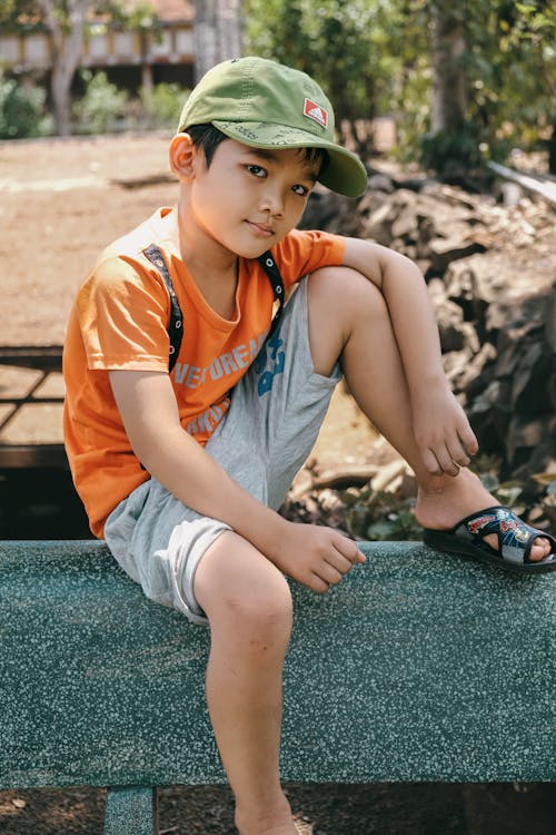 A Little Boy in a Casual Summer Outfit Sitting Outside 