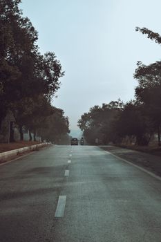 A tranquil empty road lined with trees in Islamabad, offering a peaceful rural escape.