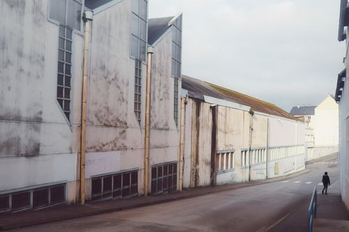 Free A solitary figure walks along an urban street in Douarnenez, France with modern architecture. Stock Photo