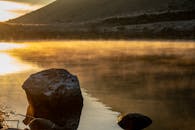 日出时分，雾气笼罩着湖边的岩石，捕捉了大自然宁静的一刻