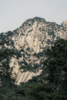 Explore a stunning view of a steep eroded mountain surrounded by lush greenery, perfect for nature enthusiasts.