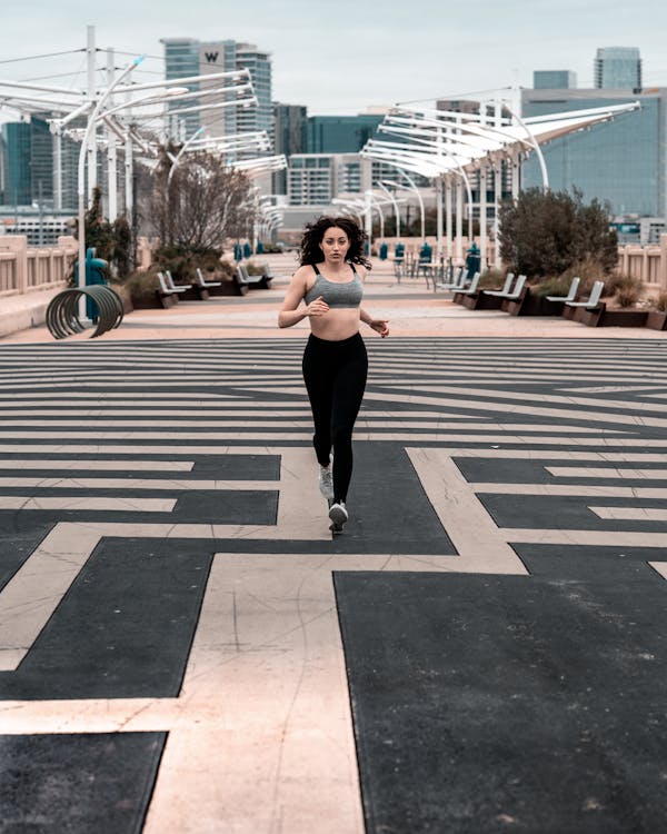 Free Woman In Grey Sports Bra Running On Road Stock Photo