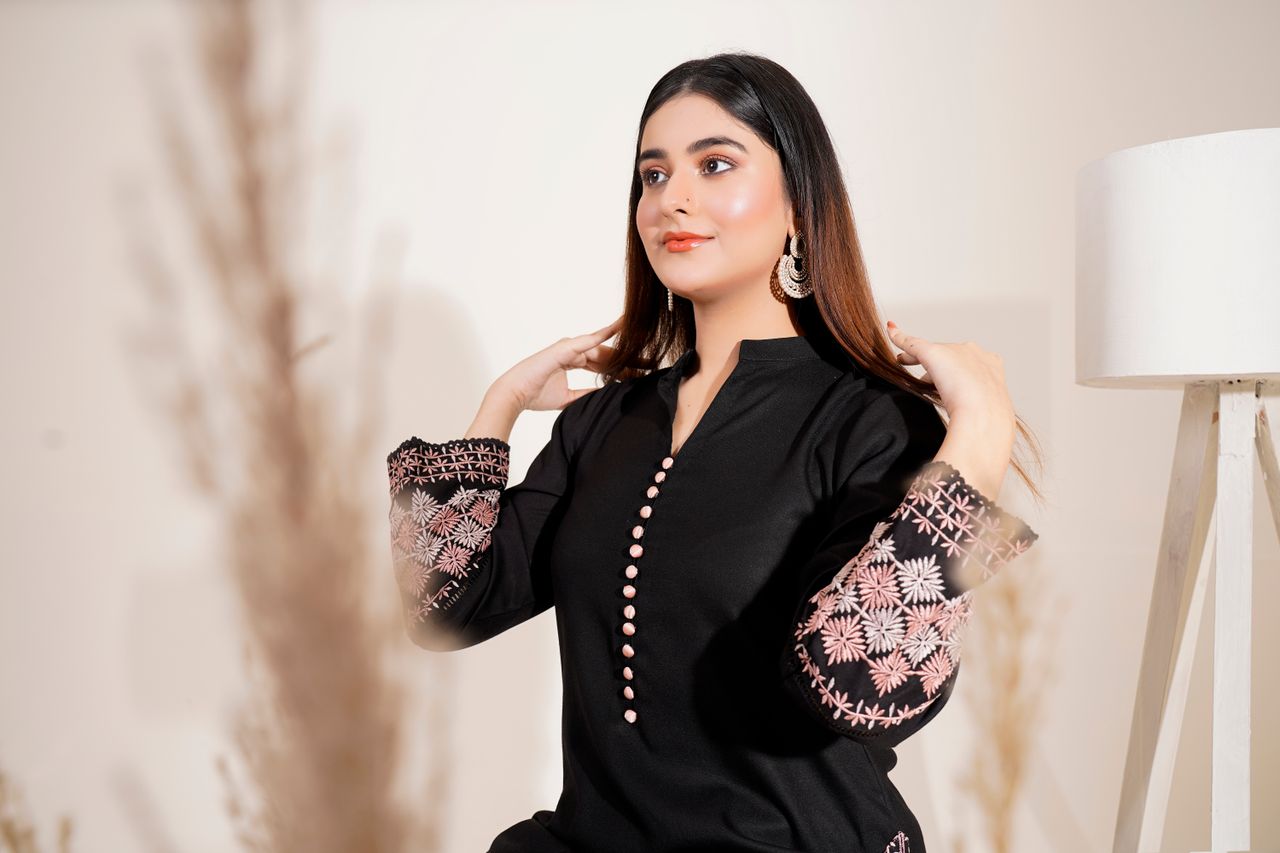 fashionable woman in an embroidered dress posing elegantly indoors