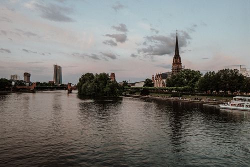 Free Beautiful evening view of Frankfurt featuring the river, cathedral, and urban skyline. Stock Photo