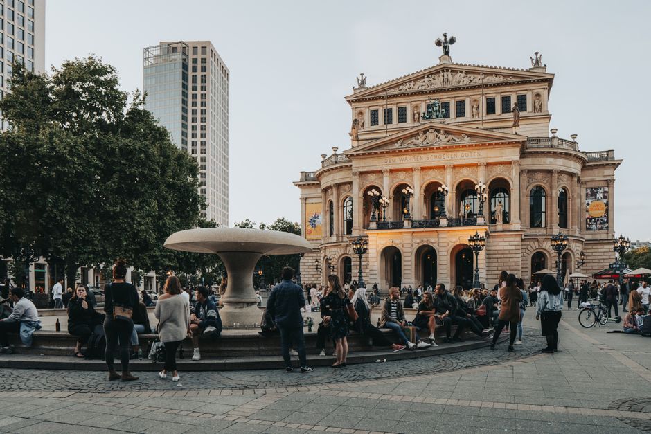 A lively evening at the Alte Oper in Frankfurt, Germany with people enjoying the town square.