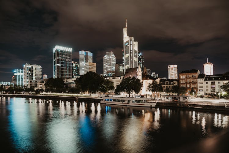 Ferry Moored At The Stop On The Main River In The Financial District Of Frankfurt At Night