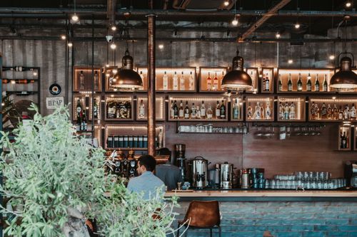 Free Modern bar interior featuring illuminated shelves and brass lamps. Ideal for nightlife themes. Stock Photo