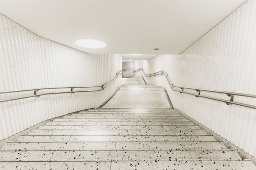Free A monochromatic view of a white-tiled subway staircase with sleek handrails and geometric design. Stock Photo