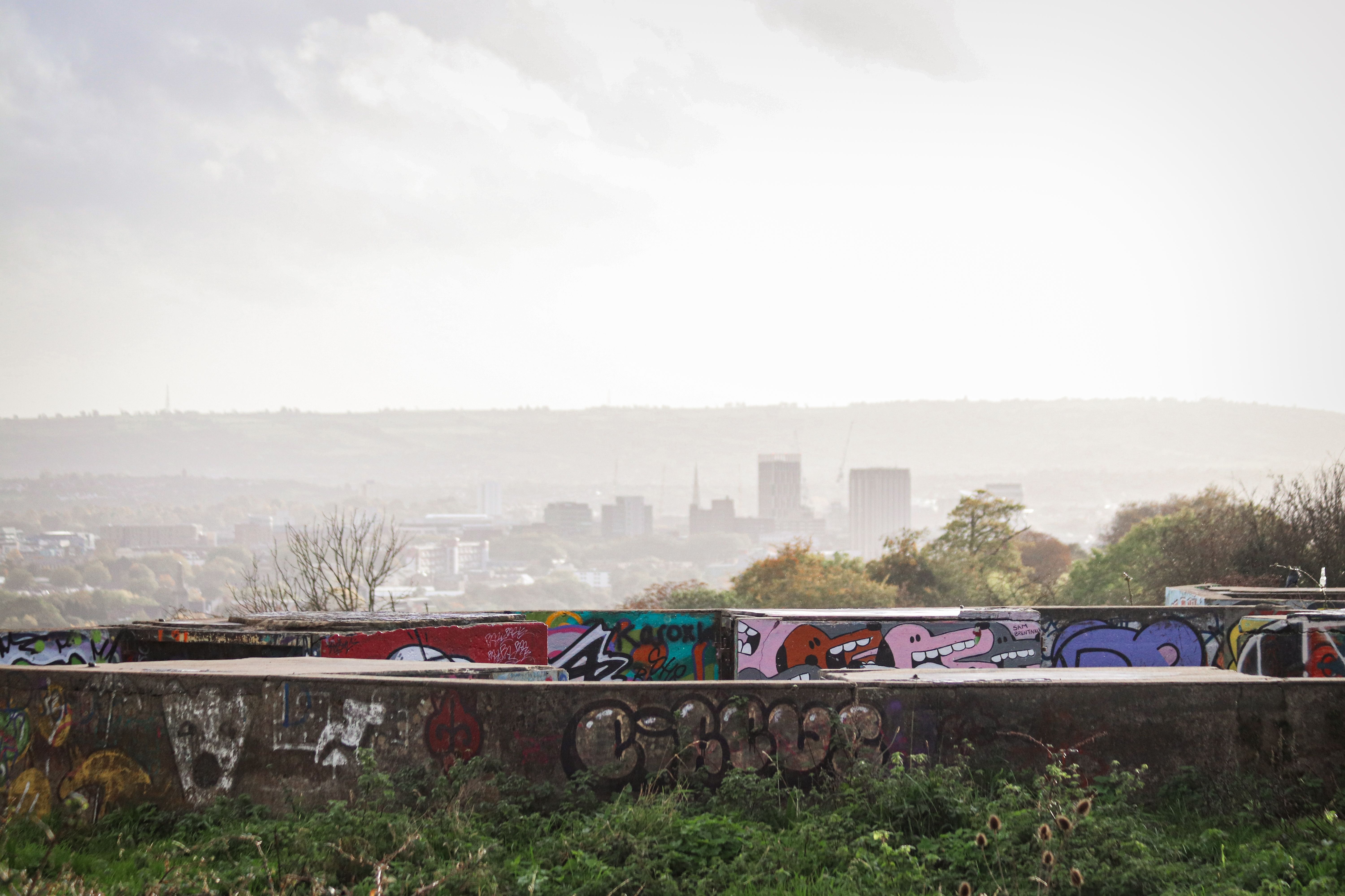 Vibrant graffiti art on an urban wall in Bristol with a city skyline backdrop.
