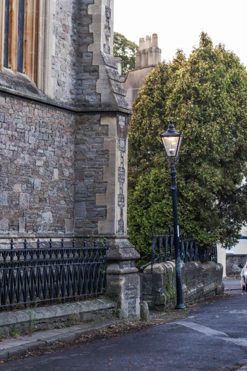 Free A vintage streetlight illuminates the cobblestone street beside a historic stone building. Stock Photo