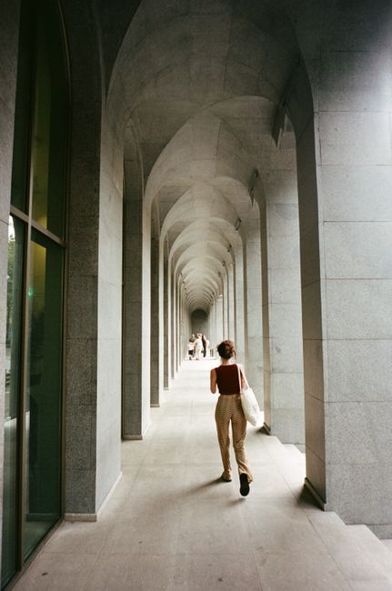 A woman walks through a grand stone arcade with archways in Tbilisi, Georgia.