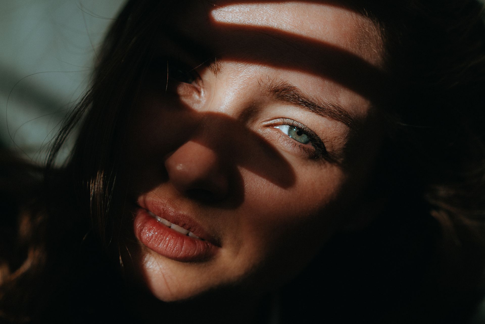 A captivating close-up portrait of a woman partially shadowed, highlighting her green eyes and natural beauty.