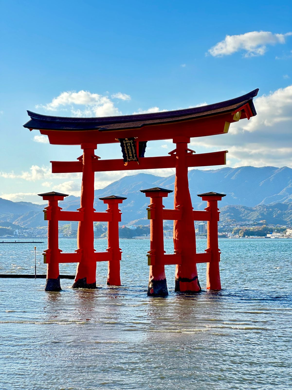 The vermilion torii gate of Itsukushima Shrine reflected in calm water on Miyajima