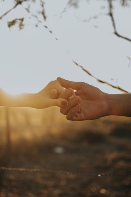 Fotomural Una pareja se toma de las manos en un gesto romántico durante un sereno atardecer en el campo.