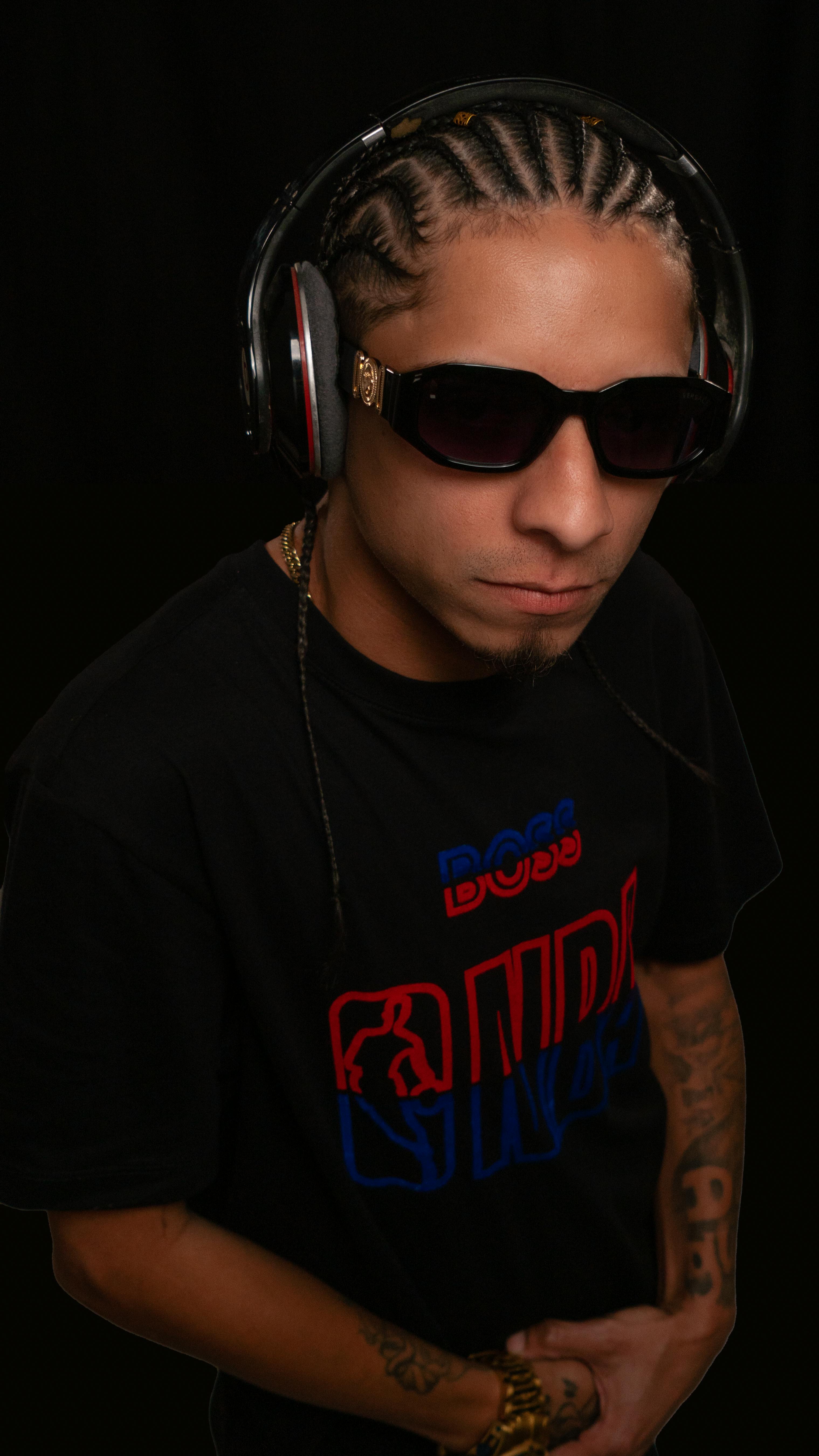 Fashionable studio portrait of a man wearing sunglasses and headphones in a black t-shirt.