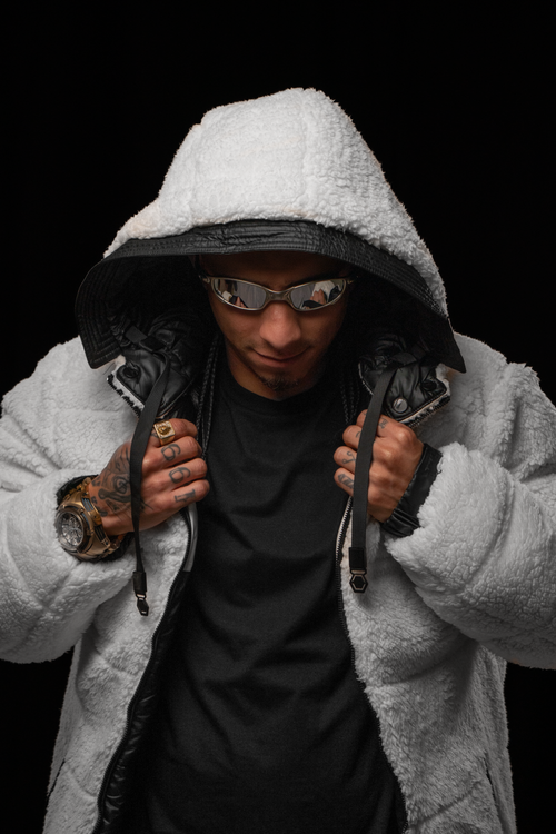 Free Fashionable model wearing a white fluffy jacket and sunglasses, posing against a black background. Stock Photo