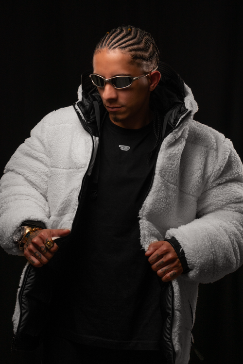 Free Portrait of a man in sunglasses, wearing a fluffy jacket against a black background. Stock Photo