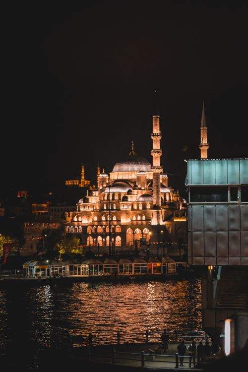 Free Beautiful night view of the illuminated New Mosque reflecting on the water in Istanbul, Turkey. Stock Photo