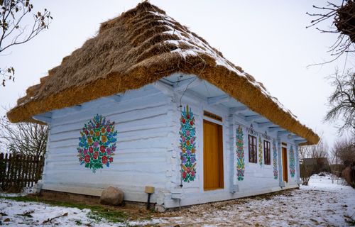 Free A traditional thatched cottage with colorful murals set against a snowy backdrop, exemplifying rustic charm. Stock Photo