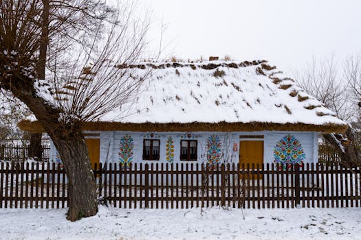 Charming wooden cottage with colorful art, snow-covered roof, in a peaceful winter setting.