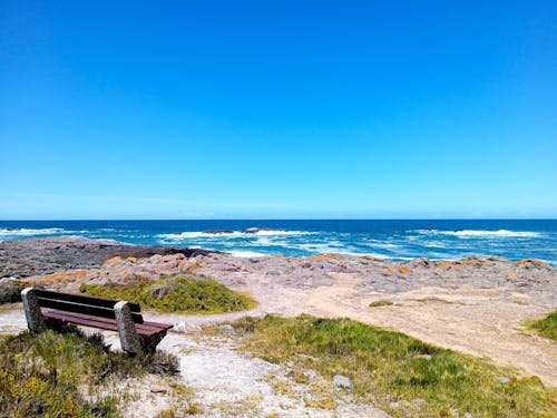 Бесплатное стоковое фото с вид на море, голубое небо, деревянная скамейка
