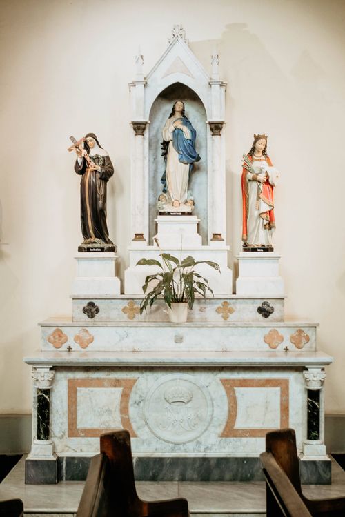 Free Catholic church altar featuring statues of saints and the Virgin Mary in a serene setting. Stock Photo