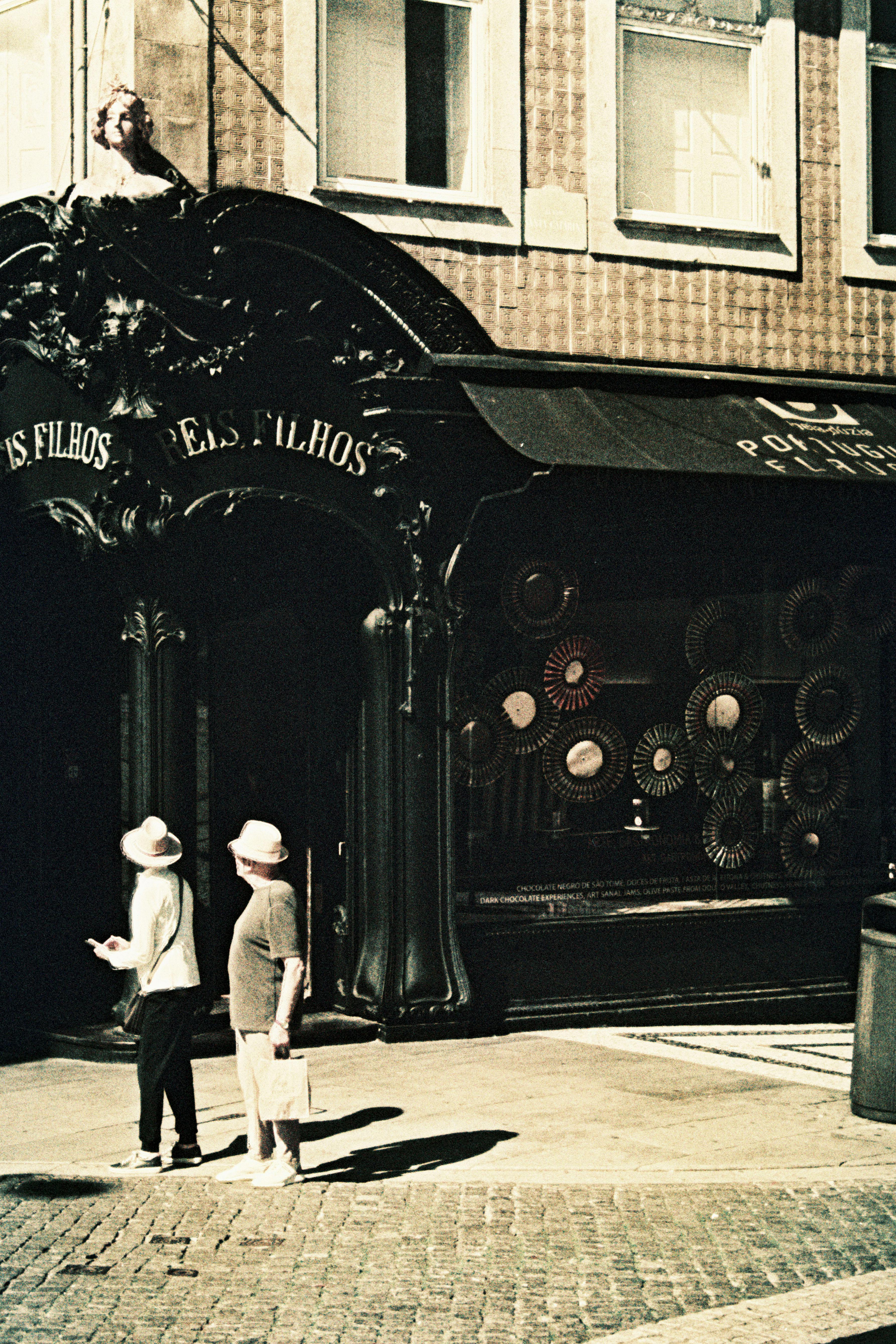 A vintage street scene capturing the historic charm of Porto with two elderly women walking by a classic facade.