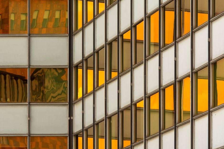 Abstract view of modern office building facade with reflective glass and geometric pattern.