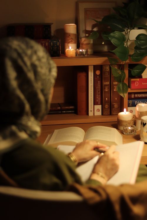 Free A serene moment of reading in a warmly lit home with candles and books. Stock Photo
