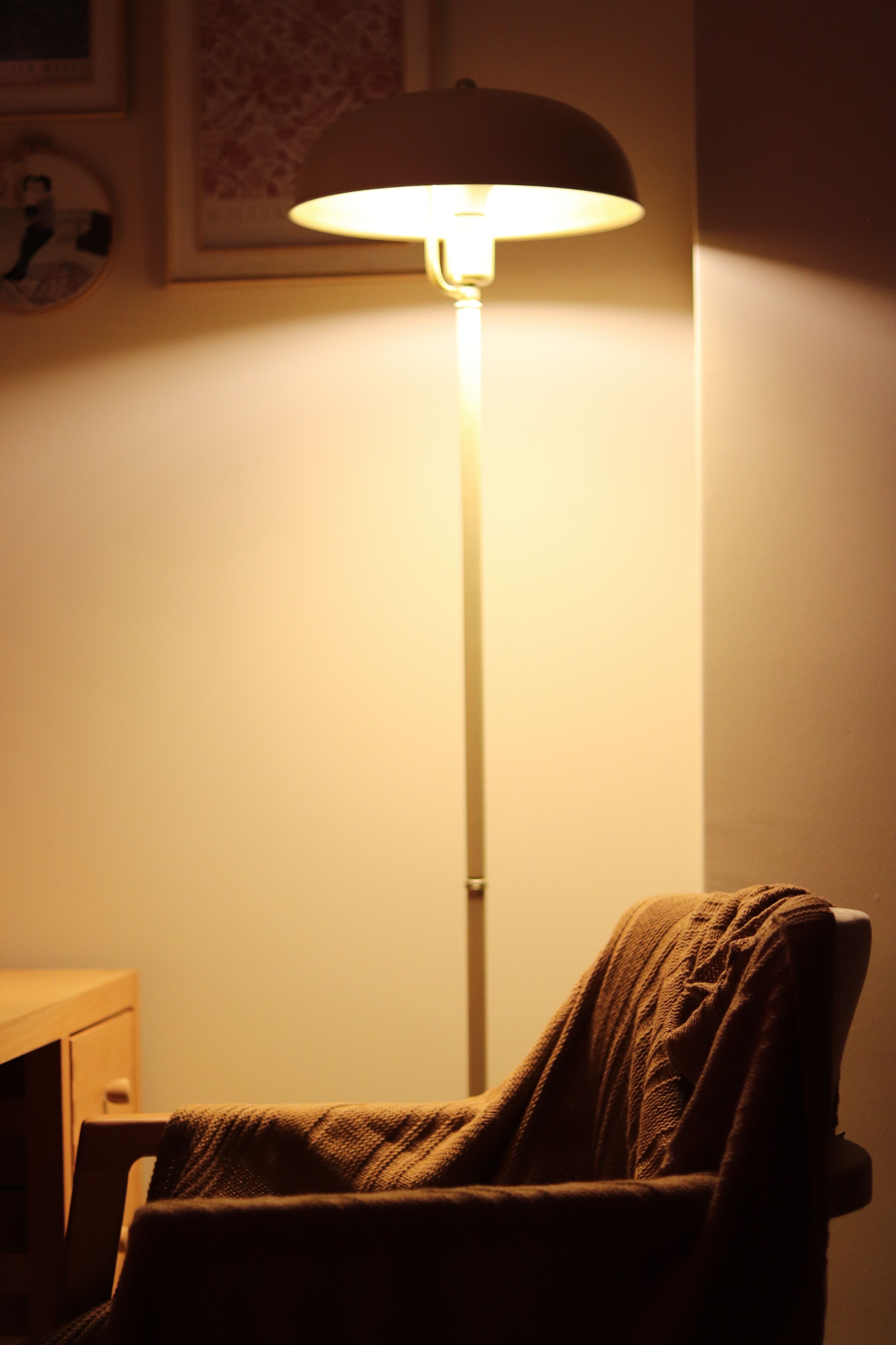 A cozy armchair and lamp create a warm ambiance in a dimly lit home interior.