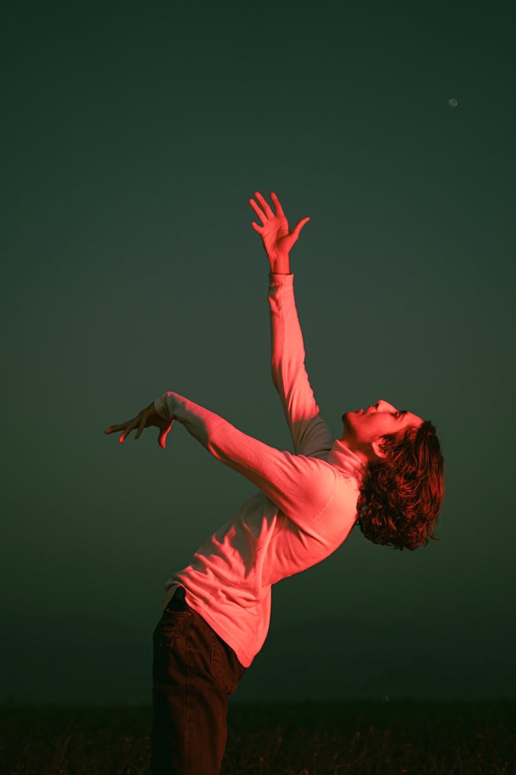 Young Man Gesturing Against The Sky At Night