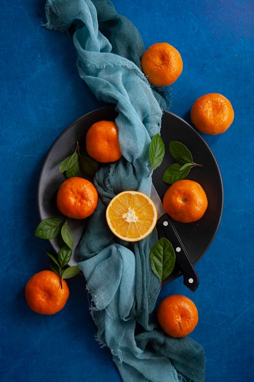 Cut Orange Among Clementines and a Knife