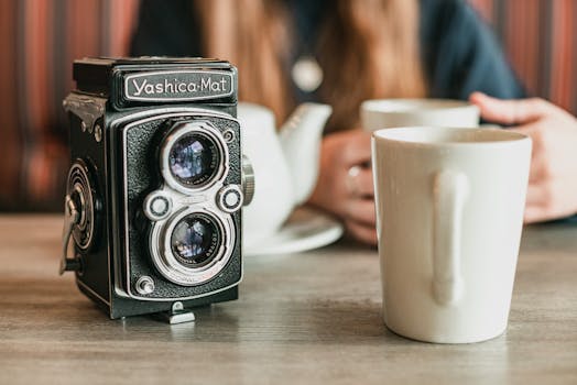 A vintage Yashica-Mat camera beside a coffee mug in a cozy setting.