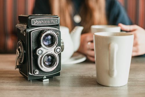 Free A vintage Yashica-Mat camera beside a coffee mug in a cozy setting. Stock Photo